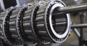 Close up view of four Timken tapered roller bearings hanging on a rack in a manufacturing facility.