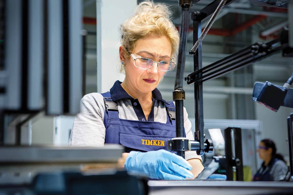 timken-assembly-gloves Una mujer con gafas de seguridad montando piezas en un banco de trabajo