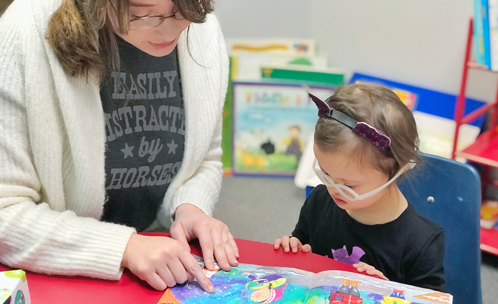 A young girl looking at a picture book at GiGi's House.